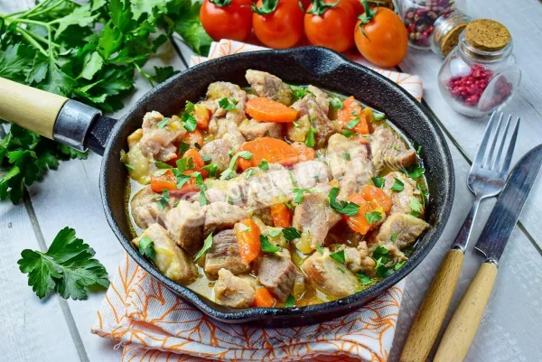 Свинина з цибулею і морквою на сковороді