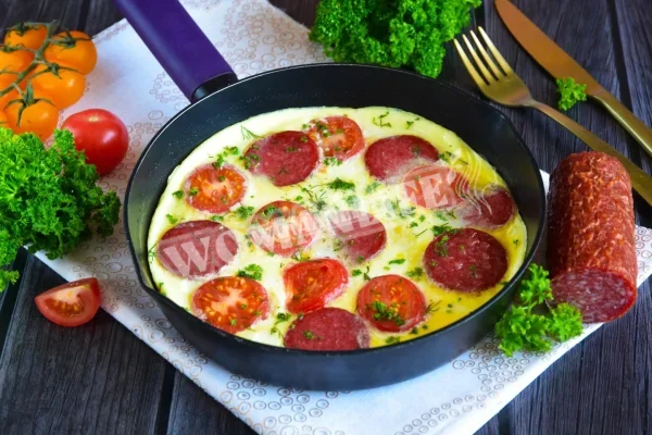 Омлет на сковороді з ковбасою і помідорами