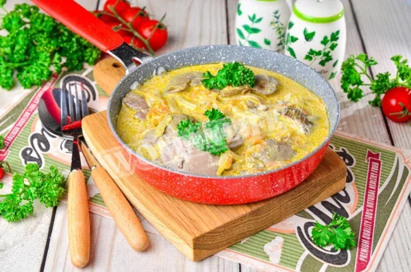 Куряча печінка, тушкована з цибулею і морквою в сметані на сковороді
