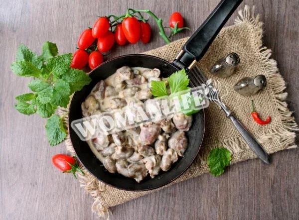 Тушковані курячі сердечка в сметані на сковороді з цибулею
